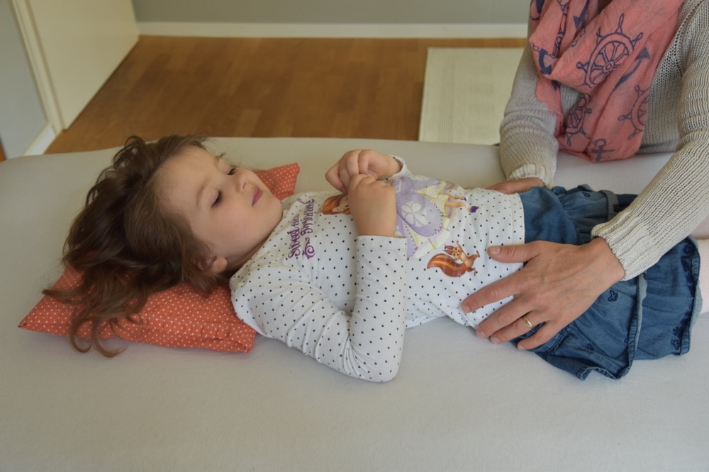 Cranio Sacral Therapeutin behandelt liegendem Jungen
